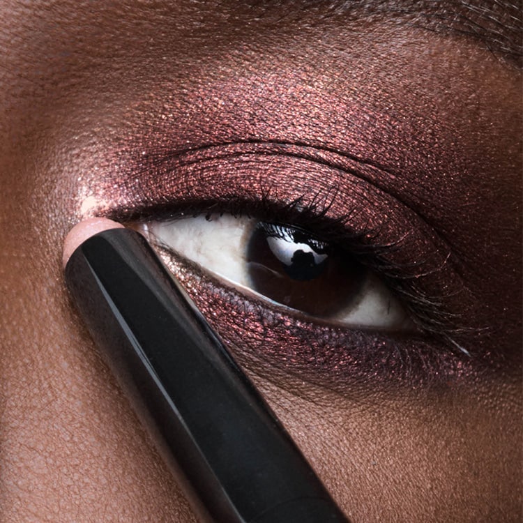Close up of model applying Long-Wear Cream Eyeshadow Stick to eyelid for a shimmering look